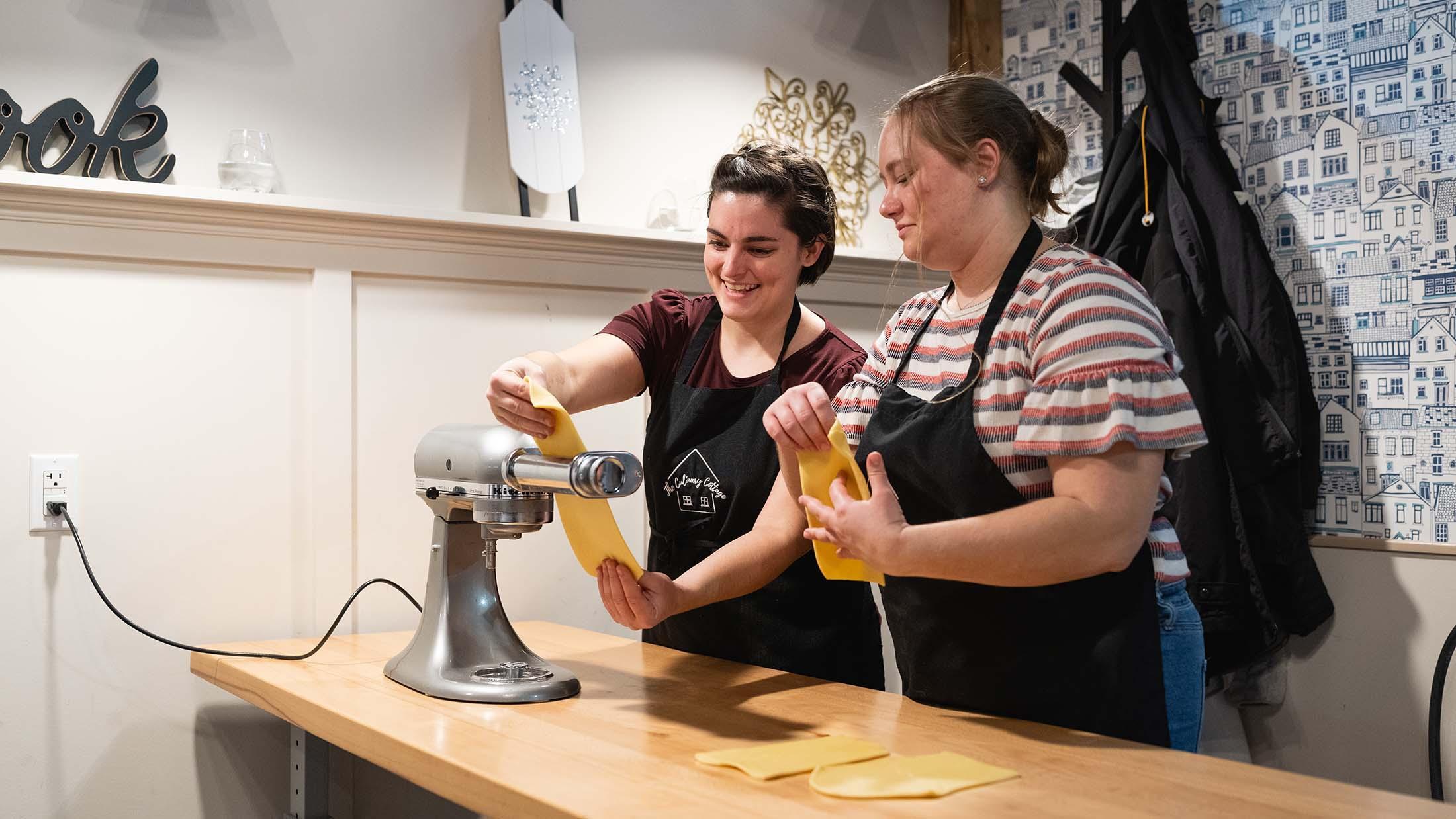 Two people making pasta at a cooking class.
