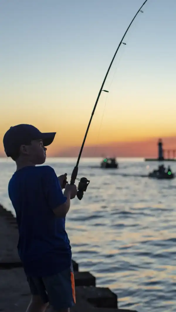 A child fishing from a pier at sunset.
