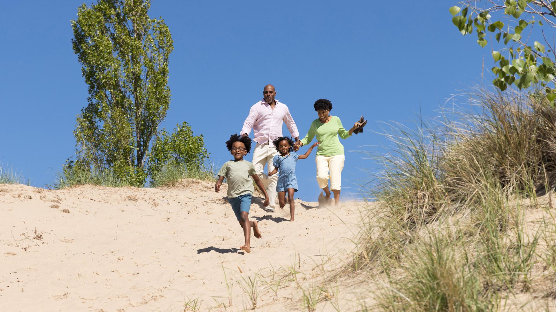 a family running down the sand dunes at tiscornia beach